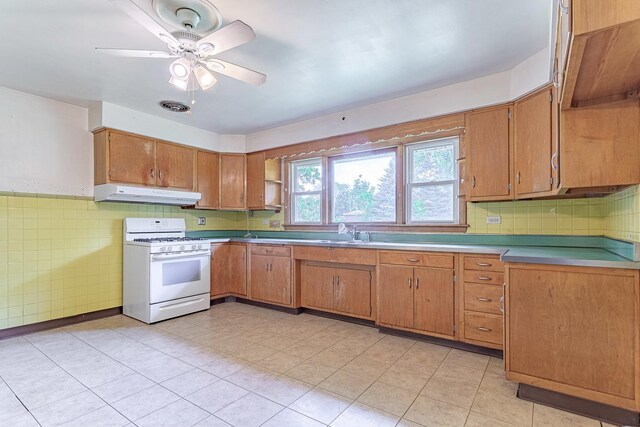 1481 Bloomingdale Rd, Glendale Heights, IL 60139 - kitchen featuring gas range gas stove, under cabinet range hood, light tile patterned floors, brown cabinetry, and tile walls