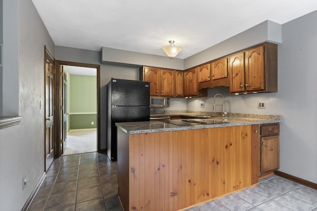 1485 Bryn Mawr Ln, Rockford, IL 61107 - kitchen featuring black appliances, a peninsula, brown cabinets, dark stone countertops, and dark tile patterned floors