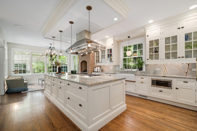 2131 W Schiller St, Chicago, IL 60622 - kitchen featuring backsplash, island exhaust hood, white cabinets, light wood-style flooring, and crown molding