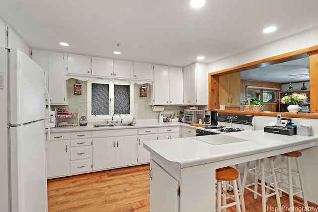 3914 N Richmond Rd, Johnsburg, IL 60051 - kitchen with white appliances, a peninsula, light wood finished floors, backsplash, and white cabinetry
