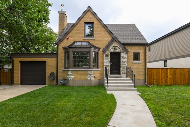 5309 Crain St, Skokie, IL 60077 - tudor house with a chimney, a garage, concrete driveway, stone siding, and brick siding