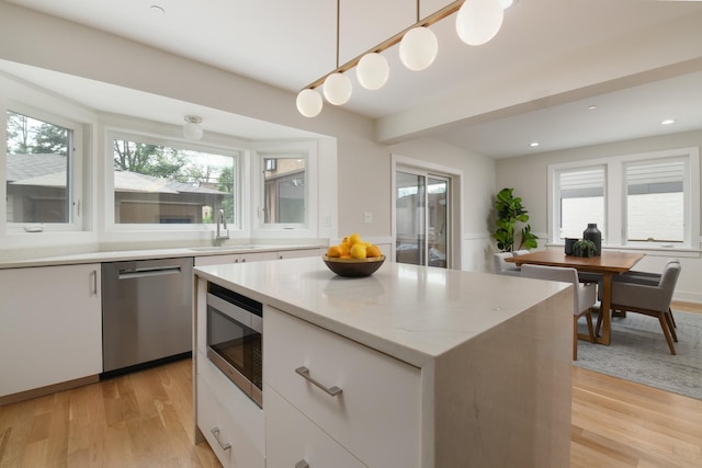 5309 Crain St, Skokie, IL 60077 - kitchen with appliances with stainless steel finishes, white cabinetry, light wood-style flooring, decorative light fixtures, and a kitchen island