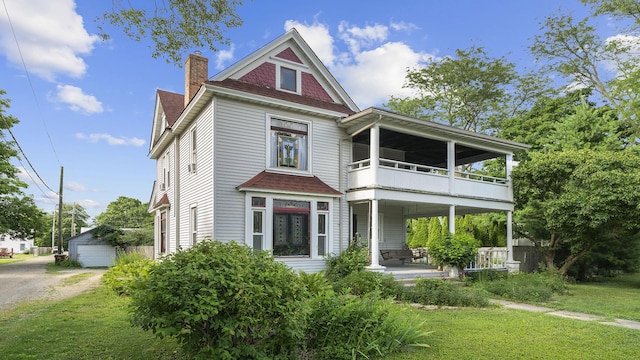 123 E 3rd St, Byron, IL 61010 - victorian house with a balcony, a front yard, an outbuilding, a chimney, and roof with shingles