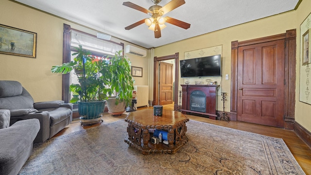 123 E 3rd St, Byron, IL 61010 - living room with wood finished floors, an AC wall unit, radiator heating unit, ceiling fan, and a fireplace