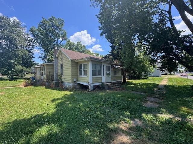 203 N Center St, Colfax, IL 61728 - view of home's exterior featuring a yard and a chimney