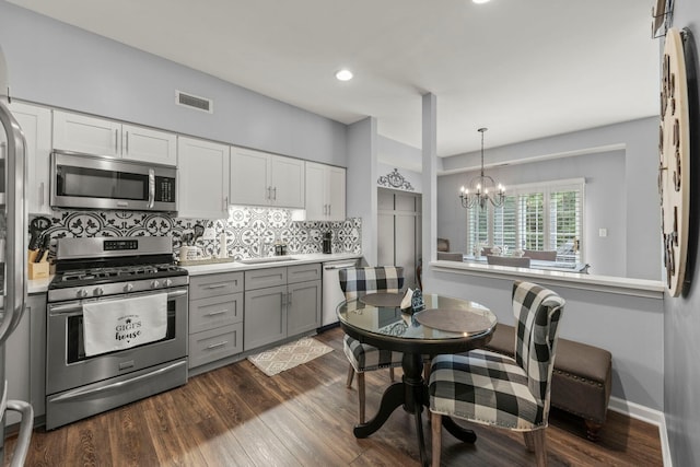 2406 Georgetown Cir, Aurora, IL 60503 - kitchen with appliances with stainless steel finishes, tasteful backsplash, gray cabinets, dark wood finished floors, and a chandelier