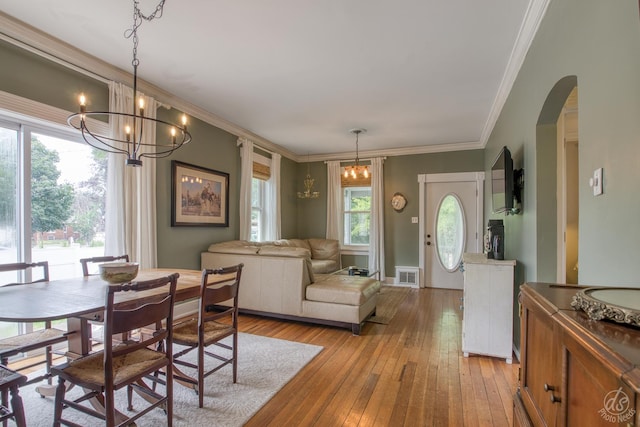 275 N Main St, Crystal Lake, IL 60014 - dining room featuring healthy amount of natural light, arched walkways, light wood-style flooring, a chandelier, and ornamental molding