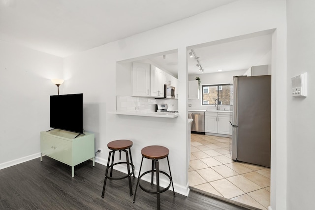 7409 N Seeley Ave Unit 2B, Chicago, IL 60645 - kitchen featuring appliances with stainless steel finishes, a kitchen bar, white cabinetry, and a peninsula