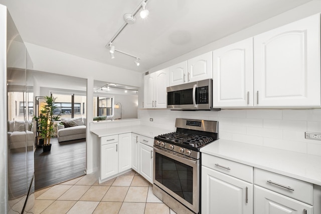 7409 N Seeley Ave Unit 2B, Chicago, IL 60645 - kitchen with stainless steel appliances, backsplash, light countertops, white cabinetry, and light tile patterned floors