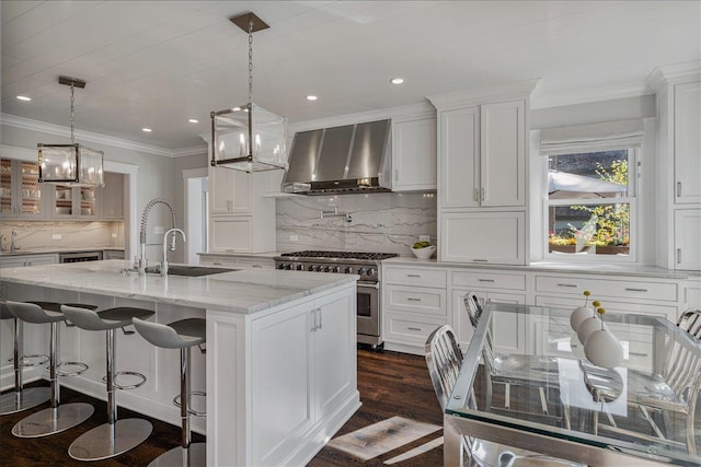 330 Abbotsford Rd, Kenilworth, IL 60043 - kitchen featuring wall chimney exhaust hood, high end stove, white cabinetry, decorative backsplash, and a center island with sink