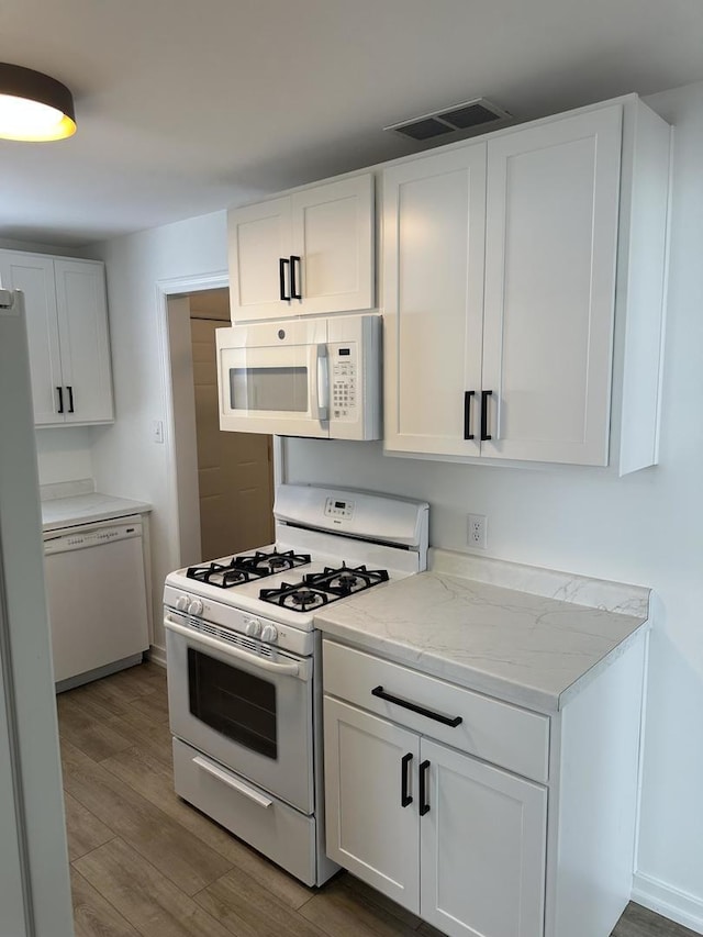 925 E Sangamon Ave, Rantoul, IL 61866 - kitchen featuring white appliances, wood finished floors, white cabinetry, and light stone counters
