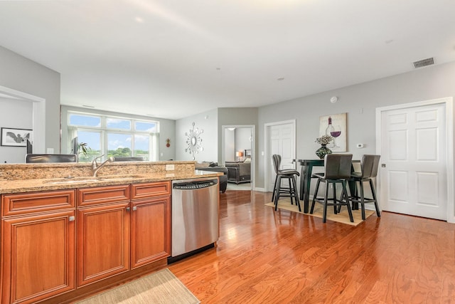 140 S River St Unit 307, Aurora, IL 60506 - kitchen featuring dishwasher, light wood-style flooring, light stone counters, brown cabinets, and open floor plan