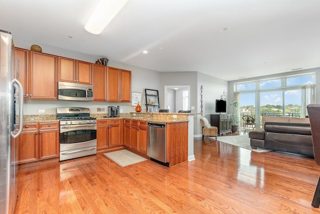 140 S River St Unit 307, Aurora, IL 60506 - kitchen with stainless steel appliances, open floor plan, a peninsula, light wood-style floors, and light stone counters