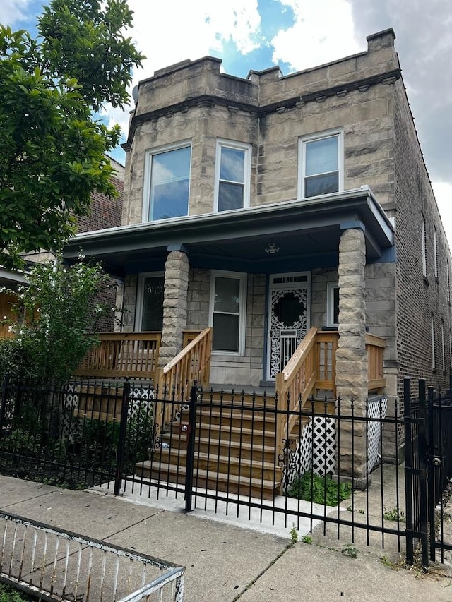 730 N Spaulding Ave, Chicago, IL 60624 - view of front facade with a porch, a fenced front yard, stone siding, and stairs