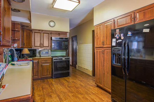 4751 S Hamlin Ave, Chicago, IL 60632 - kitchen featuring black appliances, tile walls, wood finished floors, brown cabinetry, and a wainscoted wall