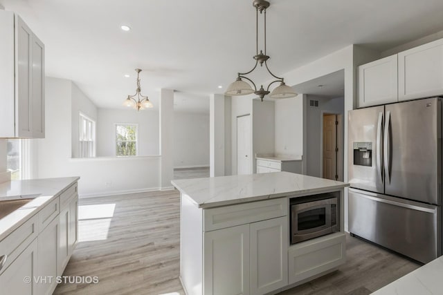 2895 Lahinch Ct, Aurora, IL 60503 - kitchen with appliances with stainless steel finishes, light wood finished floors, light stone countertops, a chandelier, and hanging light fixtures