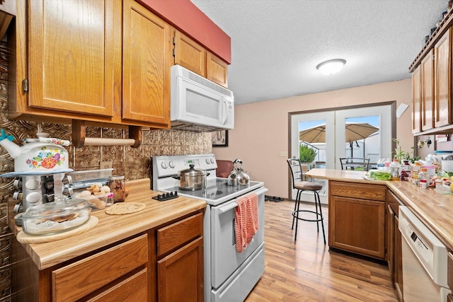 16383 US Highway 52, Newark, IL 60541 - kitchen with white appliances, light wood-type flooring, brown cabinets, a peninsula, and tasteful backsplash