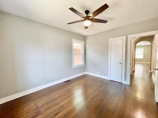 9302 S Eberhart Ave, Chicago, IL 60619 - unfurnished bedroom featuring arched walkways, dark wood-type flooring, and ceiling fan