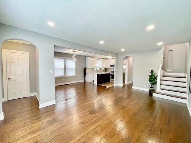 9302 S Eberhart Ave, Chicago, IL 60619 - unfurnished living room featuring arched walkways, recessed lighting, wood finished floors, and stairway