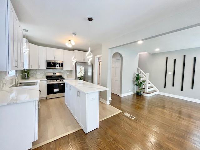 9302 S Eberhart Ave, Chicago, IL 60619 - kitchen with appliances with stainless steel finishes, backsplash, light wood-style floors, white cabinetry, and recessed lighting
