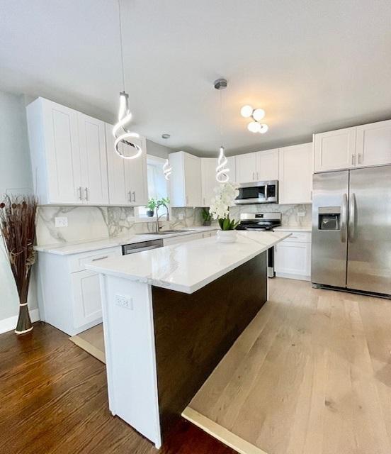 9302 S Eberhart Ave, Chicago, IL 60619 - kitchen featuring stainless steel appliances, light wood-type flooring, white cabinetry, and backsplash