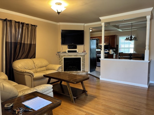 2715 W Ridgeland Ave, Waukegan, IL 60085 - living room featuring light wood-type flooring, crown molding, a chandelier, a fireplace with raised hearth, and ornate columns