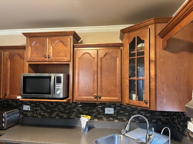2715 W Ridgeland Ave, Waukegan, IL 60085 - kitchen featuring stainless steel microwave, decorative backsplash, crown molding, glass insert cabinets, and brown cabinetry