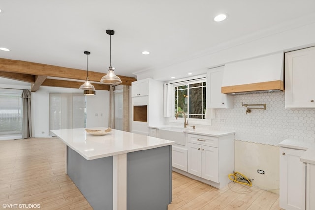 1315 Ardmore Dr, Round Lake Beach, IL 60073 - kitchen featuring decorative backsplash, light wood-type flooring, a kitchen island, white cabinets, and light countertops