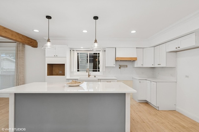 1315 Ardmore Dr, Round Lake Beach, IL 60073 - kitchen featuring premium range hood, light wood finished floors, white cabinets, a center island, and tasteful backsplash