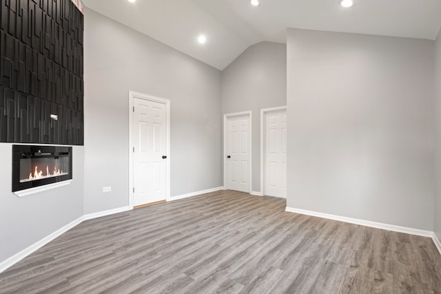 15355 7th Ave, Phoenix, IL 60426 - empty room with high vaulted ceiling, wood finished floors, a glass covered fireplace, and recessed lighting