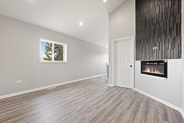 15355 7th Ave, Phoenix, IL 60426 - empty room with wood finished floors, a glass covered fireplace, high vaulted ceiling, and recessed lighting