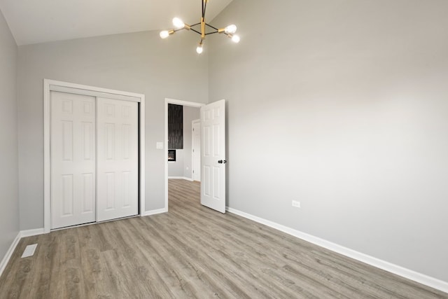 15355 7th Ave, Phoenix, IL 60426 - unfurnished bedroom with a chandelier, wood finished floors, a closet, and high vaulted ceiling