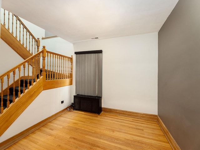 6527 N Onarga Ave, Chicago, IL 60631 - unfurnished room with radiator heating unit, wood finished floors, and stairway