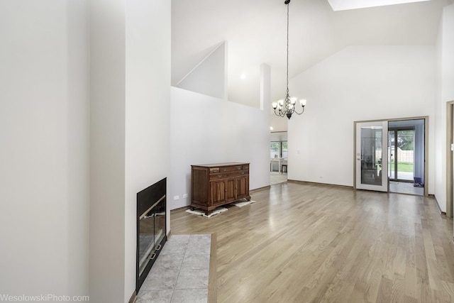 20739 N Weiland Rd, Prairie View, IL 60069 - unfurnished living room with high vaulted ceiling, healthy amount of natural light, light wood finished floors, a chandelier, and a glass covered fireplace