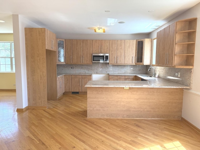 1136 Park Pl, Bellwood, IL 60104 - kitchen with stainless steel microwave, a peninsula, tasteful backsplash, and light wood-style flooring