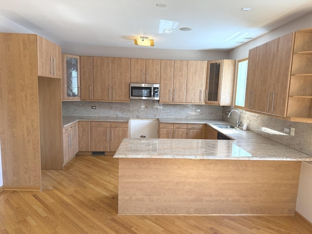 1136 Park Pl, Bellwood, IL 60104 - kitchen featuring stainless steel microwave, a peninsula, light stone counters, light wood finished floors, and tasteful backsplash