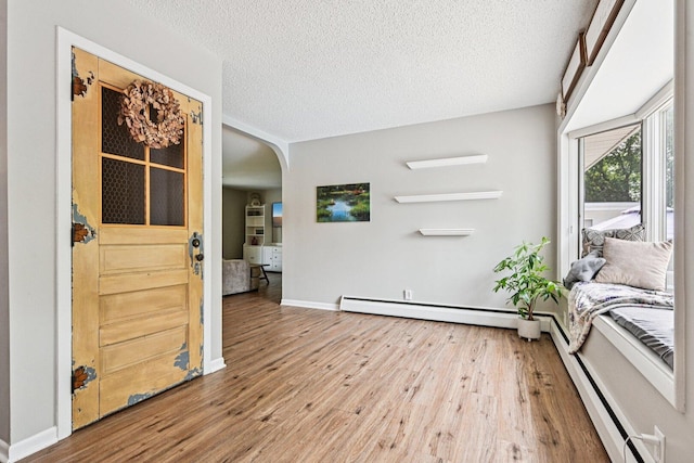 412 E S St, Peotone, IL 60468 - living area with arched walkways, wood finished floors, a textured ceiling, and a baseboard radiator