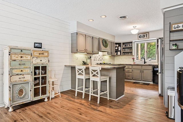 412 E S St, Peotone, IL 60468 - kitchen with a peninsula, open shelves, wood finished floors, a breakfast bar, and a textured ceiling