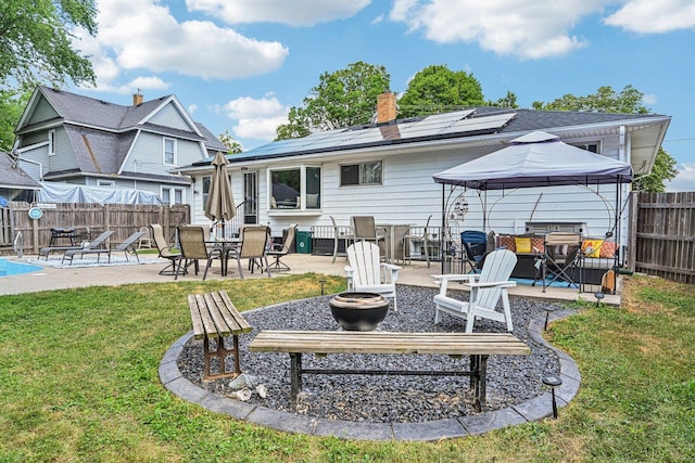 412 E S St, Peotone, IL 60468 - back of property with a fire pit, a patio area, roof mounted solar panels, a gazebo, and a fenced backyard