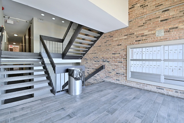 1813 Hemlock Pl Unit 306, Schaumburg, IL 60173 - staircase featuring brick wall, mail area, wood finished floors, and a towering ceiling