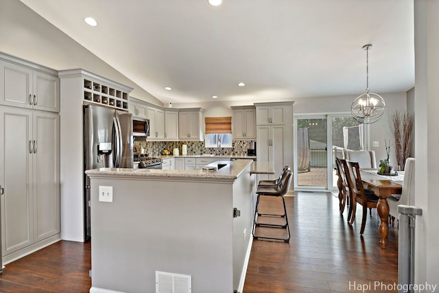 809 W Sheridan Rd, Mchenry, IL 60051 - kitchen with stainless steel appliances, a chandelier, backsplash, a kitchen island, and dark wood-style flooring
