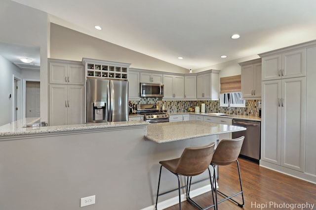 809 W Sheridan Rd, Mchenry, IL 60051 - kitchen featuring appliances with stainless steel finishes, gray cabinetry, tasteful backsplash, vaulted ceiling, and a kitchen breakfast bar
