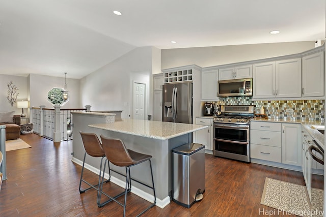 809 W Sheridan Rd, Mchenry, IL 60051 - kitchen with appliances with stainless steel finishes, vaulted ceiling, a center island, a breakfast bar area, and decorative backsplash