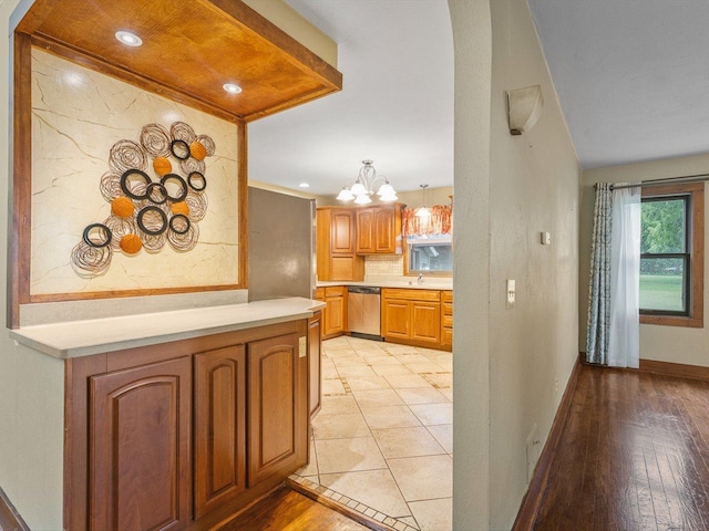 512 S Elida St, Winnebago, IL 61088 - kitchen with stainless steel dishwasher, a chandelier, light countertops, backsplash, and light wood finished floors