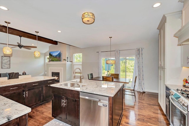 24401 S Clydesdale Ct, Manhattan, IL 60442 - kitchen featuring stainless steel appliances, open floor plan, a ceiling fan, a center island with sink, and a warm lit fireplace