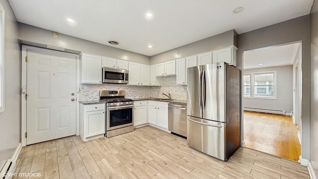 4629 Main St Unit 2A, Skokie, IL 60076 - kitchen featuring stainless steel appliances, a baseboard radiator, white cabinetry, light wood-style floors, and recessed lighting