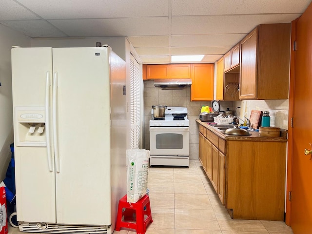 450 W 29th St, Chicago, IL 60616 - kitchen with white appliances, under cabinet range hood, a paneled ceiling, light tile patterned floors, and decorative backsplash