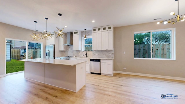 300 N Lockwood Ave, Chicago, IL 60644 - kitchen featuring a chandelier, appliances with stainless steel finishes, wall chimney exhaust hood, a center island, and light wood-style flooring