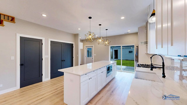 300 N Lockwood Ave, Chicago, IL 60644 - kitchen with stainless steel microwave, light wood-style flooring, white cabinetry, a center island, and recessed lighting