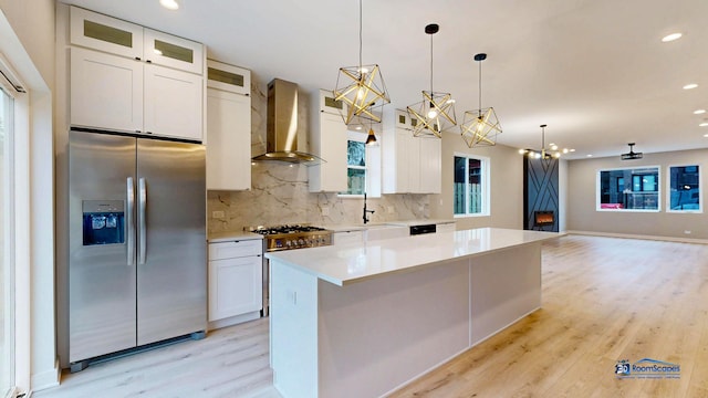 300 N Lockwood Ave, Chicago, IL 60644 - kitchen featuring appliances with stainless steel finishes, wall chimney exhaust hood, light wood-type flooring, backsplash, and white cabinetry